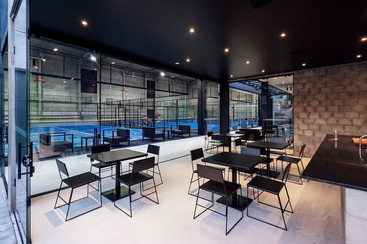 Mesas do lounge com as quadras azuis ao fundo
