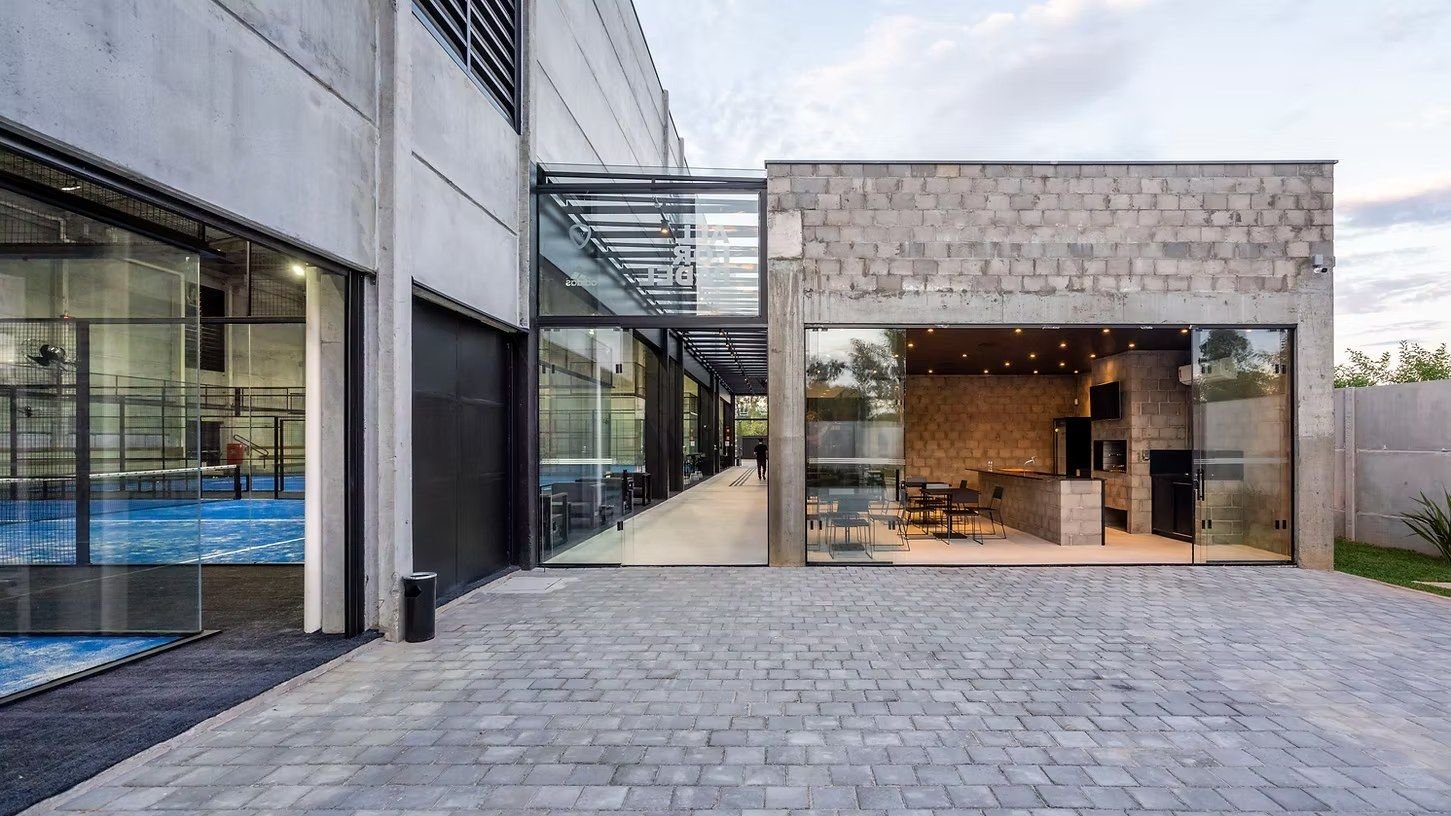 Pátio entre as quadras e o lounge, com concreto e vidro