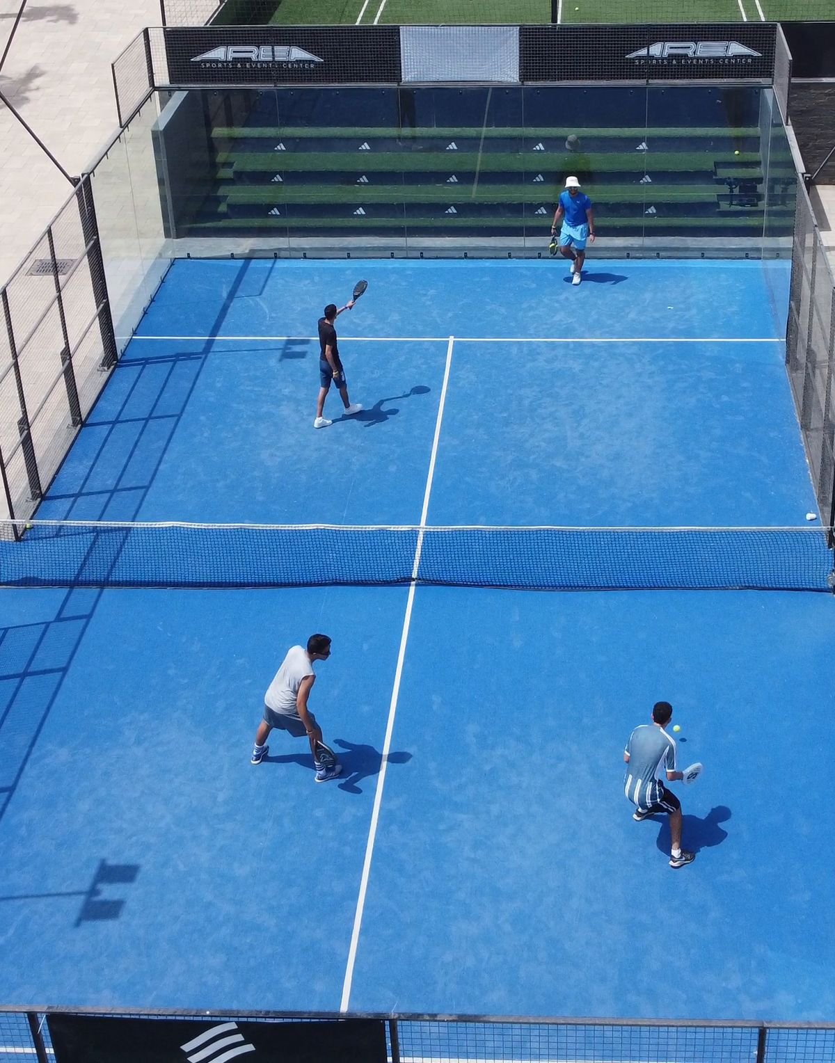Partida de padel com quatro jogadores vista do alto